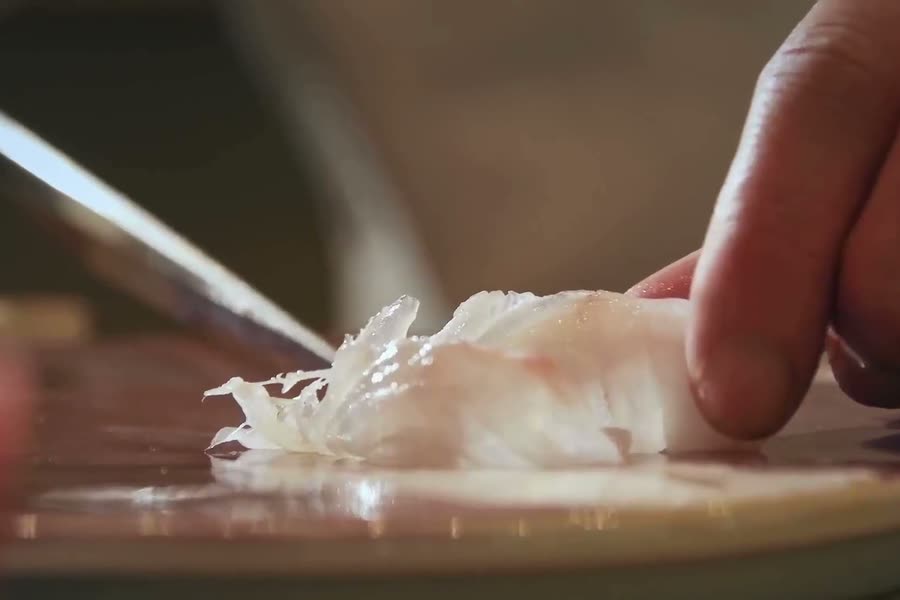 A knife slicing fish, close up